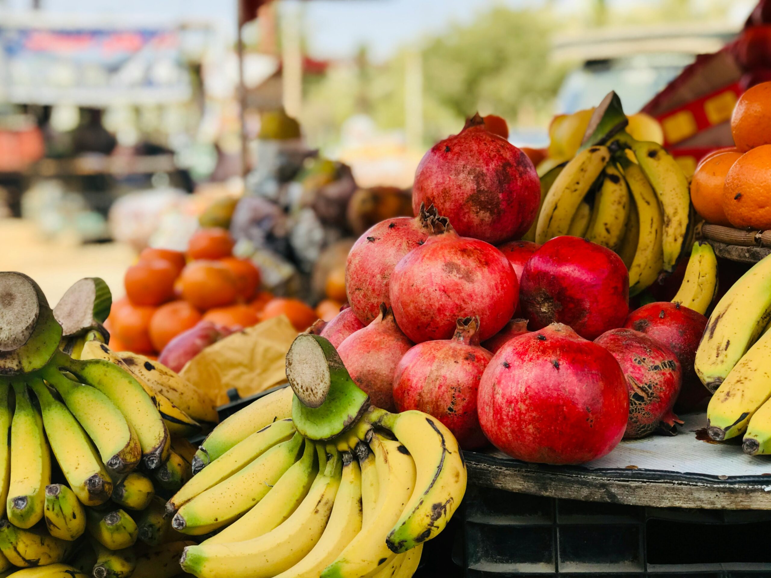 A vibrant display of bananas, pomegranates, and various fruits at an outdoor market. Fresh and healthy selection.